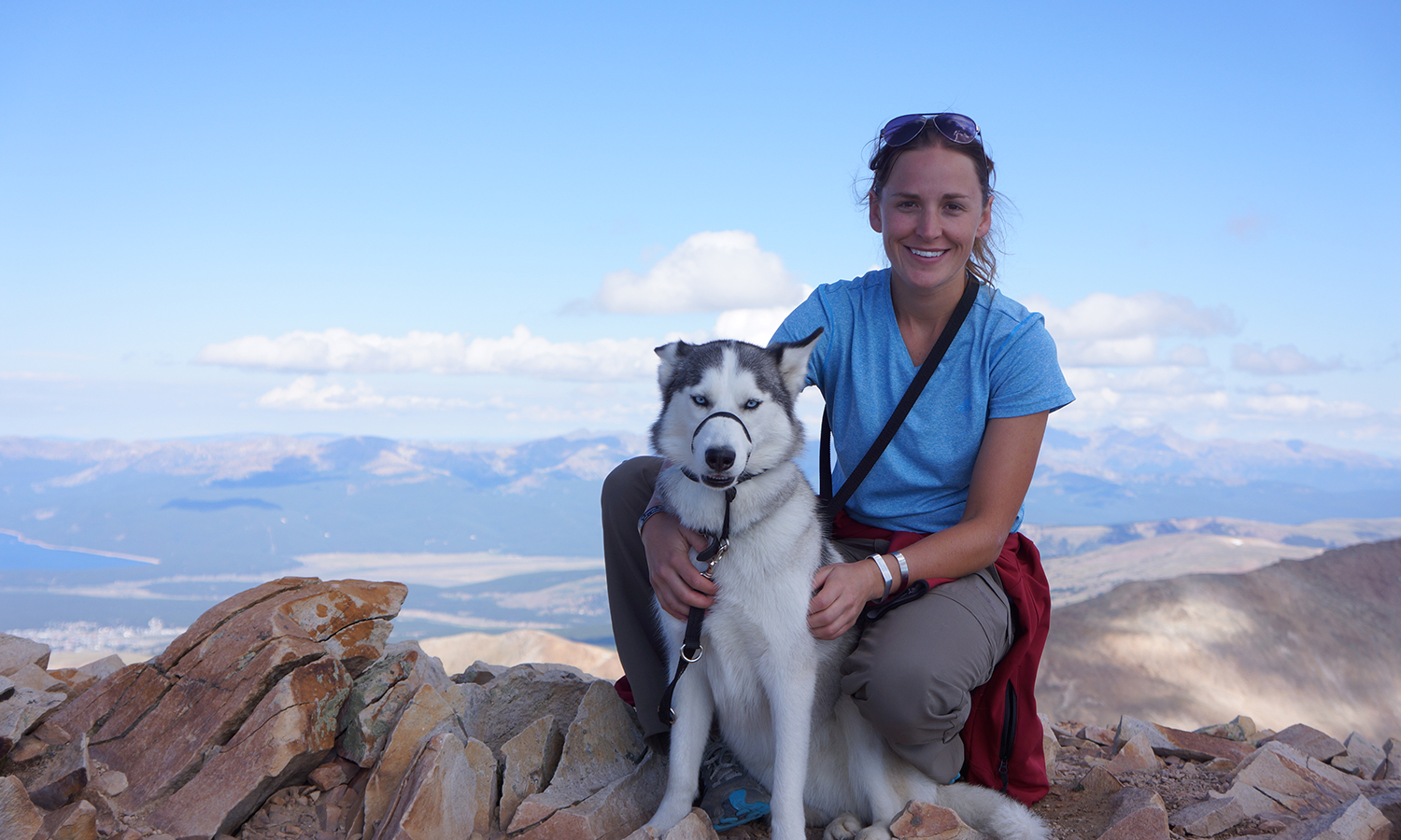 Blog Author Margaux posting a top a mountain with her dog.