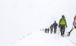 Snowy mountain with a team of climbers roped together, climbing the mountain.