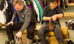 two members of team try on hiking shoes sitting on a bench within a sporting goods store