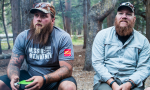 image of two men sitting by a campfire, listening to someone across from them speak